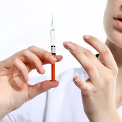 Dłoń trzyma strzykawkę z płynem, gotową do podania. To ważny krok w kierunku szczepień obowiązkowych.