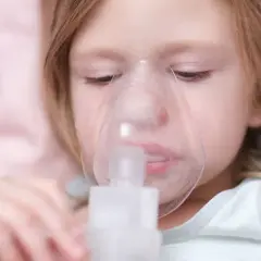 Dziewczynka z maską inhalatora na twarzy.