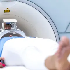 Pacjent leży w aparacie do rezonansu magnetycznego. Widoczne są jego oczy w specjalnym wizjerze, który pomaga jak przetrwać rezonans magnetyczny.