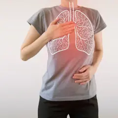 Osoba z rękami na klatce piersiowej, na której widnieje rysunek płuc z zaczerwienieniem.
