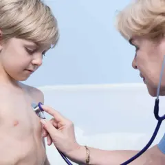 Lekarz osłuchuje klatkę piersiową chłopca, diagnozując zapalenie oskrzeli u dzieci.