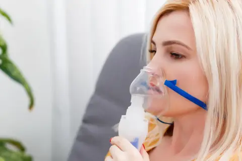 Kobieta z maską nebulizatora na twarzy.