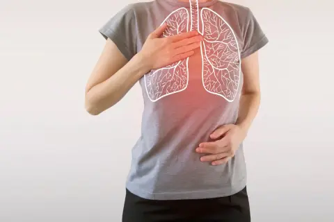 Osoba z rękami na klatce piersiowej, na której widnieje rysunek płuc z zaczerwienieniem.
