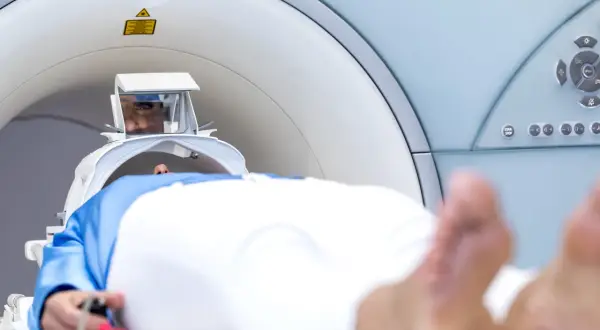 Pacjent leży w aparacie do rezonansu magnetycznego. Widoczne są jego oczy w specjalnym wizjerze, który pomaga jak przetrwać rezonans magnetyczny.