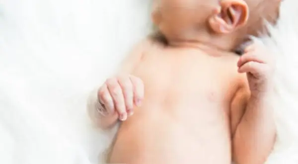 Delikatna skóra niemowlęcia, być może zmagającego się z trądzikiem niemowlęcym lub skazą białkową, otulona bielą.