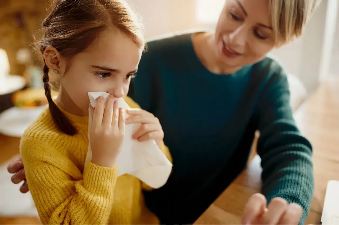 Zmartwiona mama pociesza córkę, która wydmuchuje nos. Zastanawiasz się, ile trwa kaszel u dziecka?