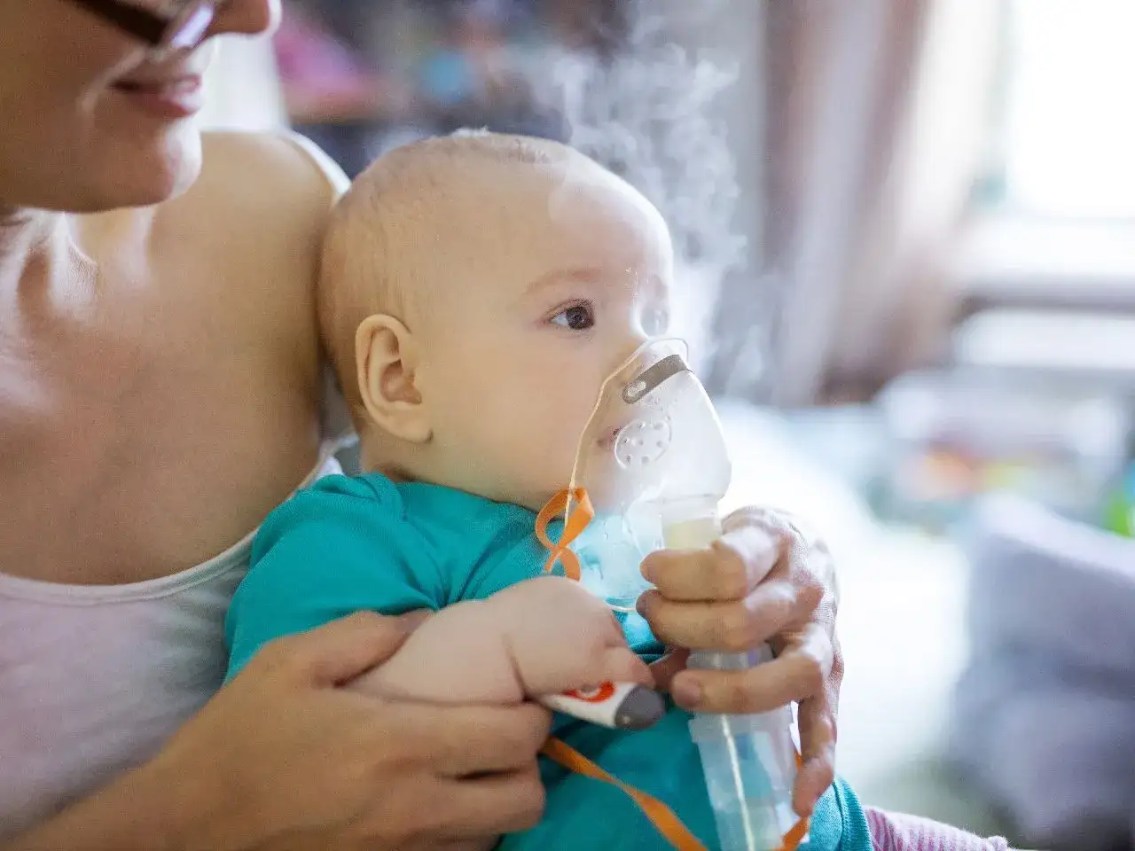 Mama robi inhalacje dla niemowlaka, który spokojnie wdycha lek.
