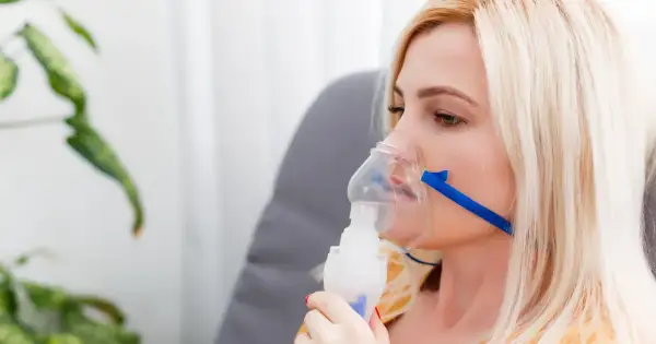 Kobieta z maską nebulizatora na twarzy.