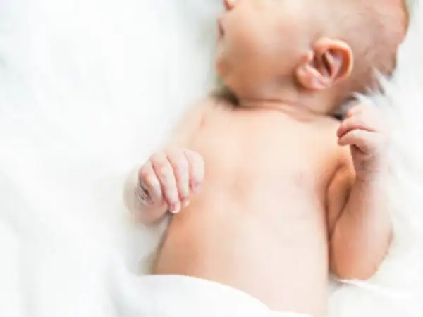 Delikatna skóra niemowlęcia, być może zmagającego się z trądzikiem niemowlęcym lub skazą białkową, otulona bielą.