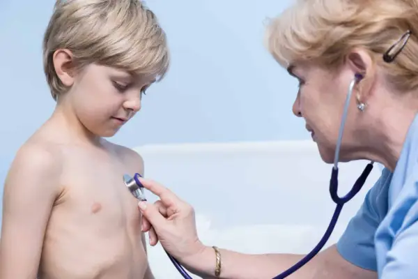 Lekarz osłuchuje klatkę piersiową chłopca, diagnozując zapalenie oskrzeli u dzieci.